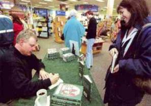 Image: Author John Snyder signs a book for a customer at Borders Books.